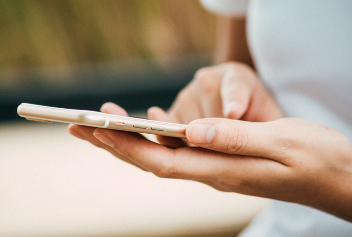 Frau hält Handy in der Hand und tippt etwas ein