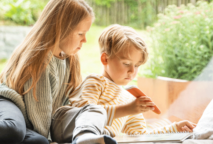 Bruder und Schwester sitzen auf Fensterbank und malen
