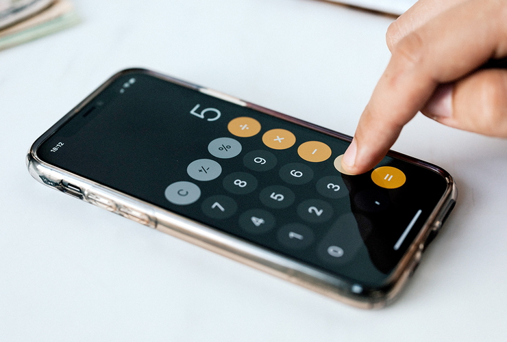 Finger tippt eine Rechnung in den Taschenrechner im Handy ein